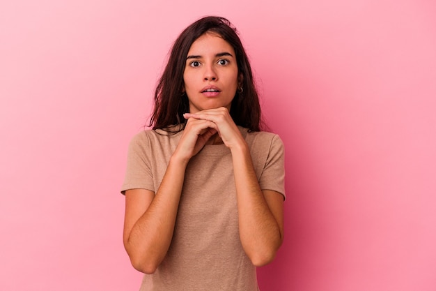 Young caucasian woman isolated on pink background praying for luck, amazed and opening mouth looking to front.