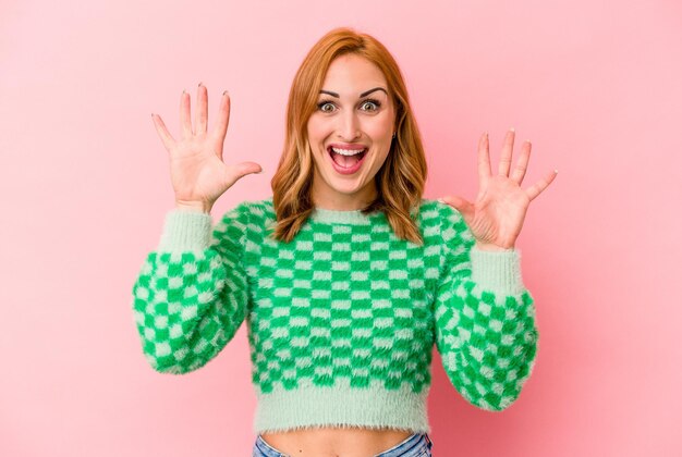 Young caucasian woman isolated on pink background receiving a pleasant surprise, excited and raising hands.