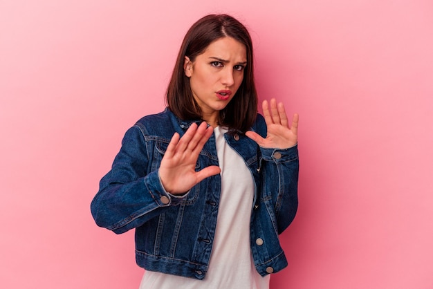 Young caucasian woman isolated on pink background rejecting someone showing a gesture of disgust