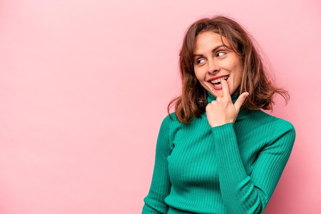 Young caucasian woman isolated on pink background relaxed thinking about something looking at a copy space