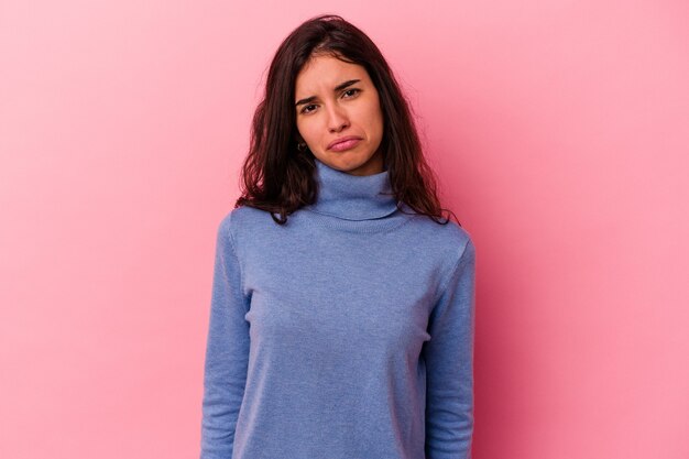 Young caucasian woman isolated on pink background sad, serious face, feeling miserable and displeased.