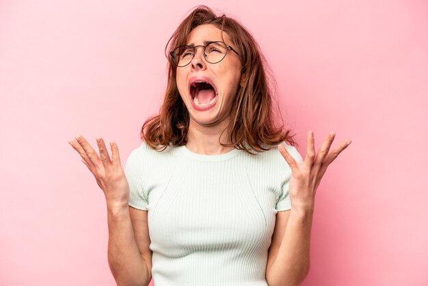 Young caucasian woman isolated on pink background screaming to the sky looking up frustrated