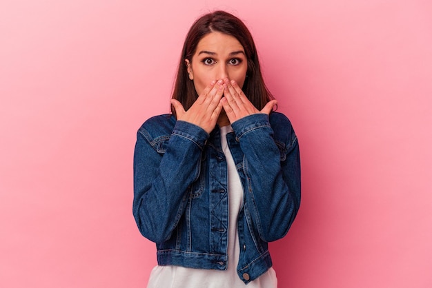 Young caucasian woman isolated on pink background shocked covering mouth with hands