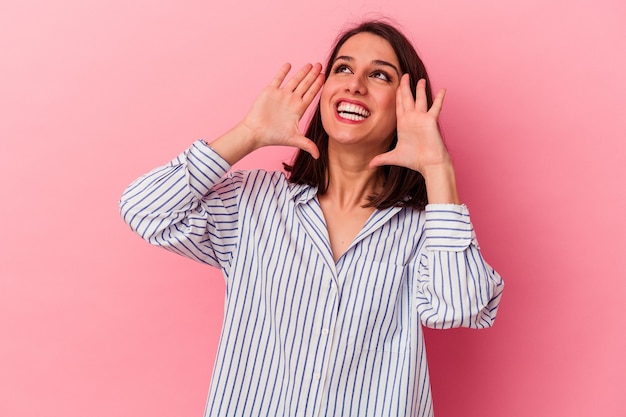 Young caucasian woman isolated on pink background shouting excited to front.