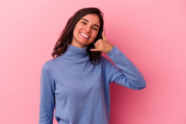 Young caucasian woman isolated on pink background showing a mobile phone call gesture with fingers.