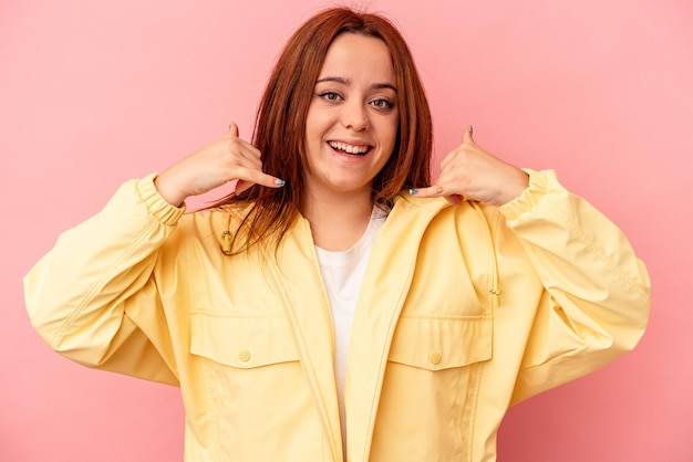 Young caucasian woman isolated on pink background showing a mobile phone call gesture with fingers.