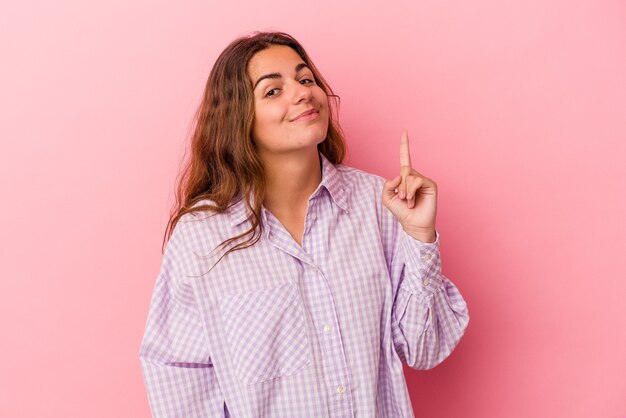 Young caucasian woman isolated on pink background  showing number one with finger.