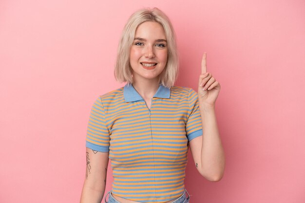 Young caucasian woman isolated on pink background showing number one with finger