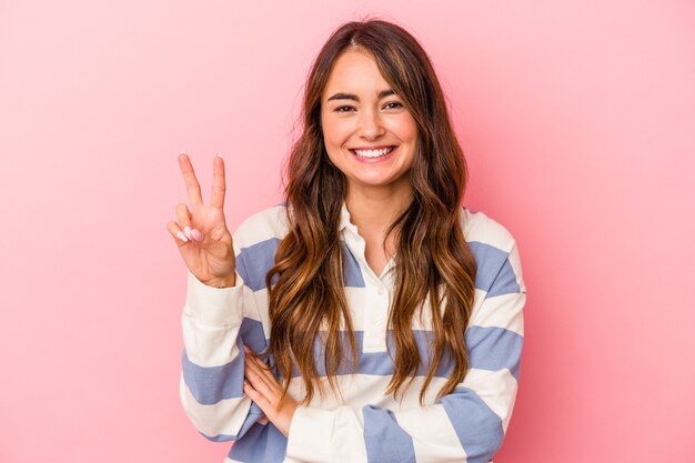 Photo young caucasian woman isolated on pink background showing number two with fingers.