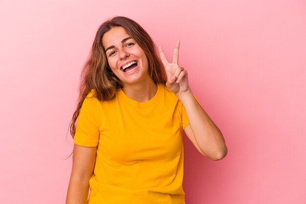 Young caucasian woman isolated on pink background  showing number two with fingers.