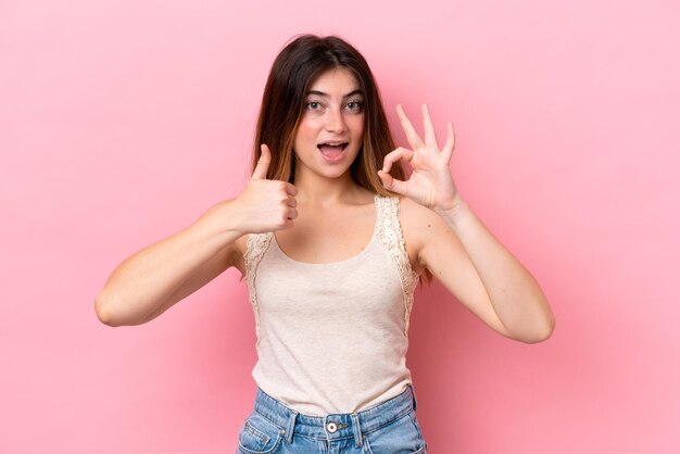 Foto giovane donna caucasica isolata su sfondo rosa che mostra il segno ok e il gesto del pollice in alto