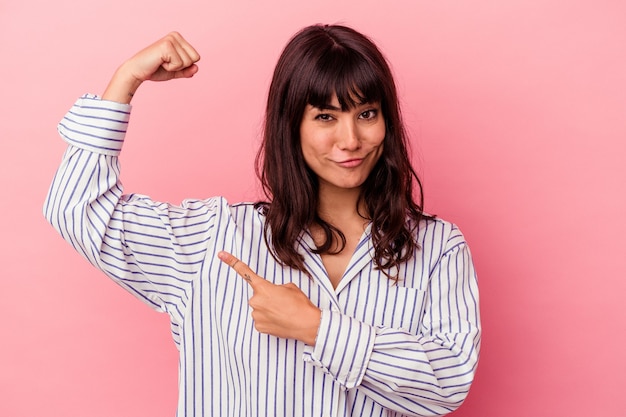 Young caucasian woman isolated on pink background showing strength gesture with arms, symbol of feminine power