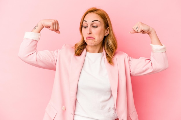 Photo young caucasian woman isolated on pink background showing strength gesture with arms, symbol of feminine power