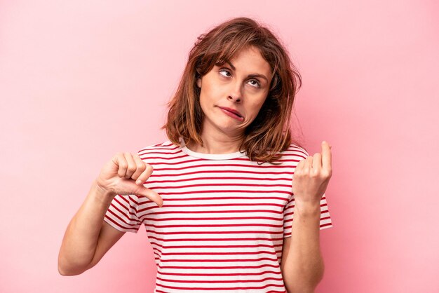 Young caucasian woman isolated on pink background showing that she has no money