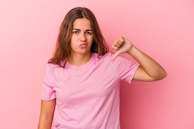 Young caucasian woman isolated on pink background  showing thumb down, disappointment concept.
