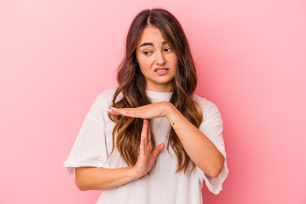 Young caucasian woman isolated on pink background showing a timeout gesture.