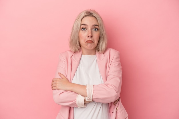 Young caucasian woman isolated on pink background shrugs shoulders and open eyes confused.