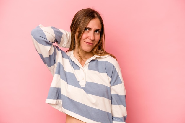 Young caucasian woman isolated on pink background suffering neck pain due to sedentary lifestyle