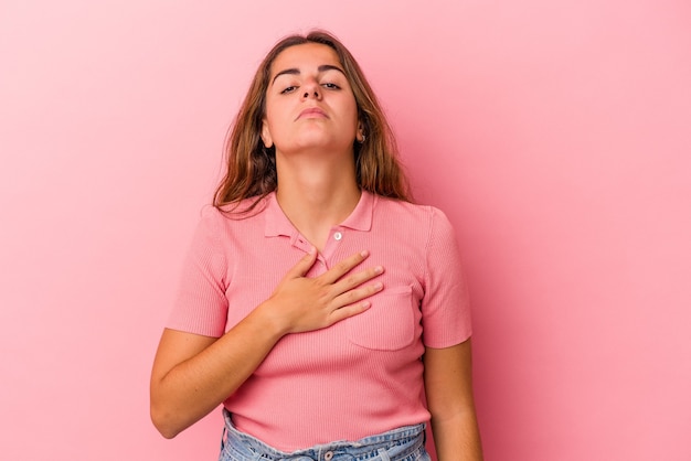 Young caucasian woman isolated on pink background  taking an oath, putting hand on chest.