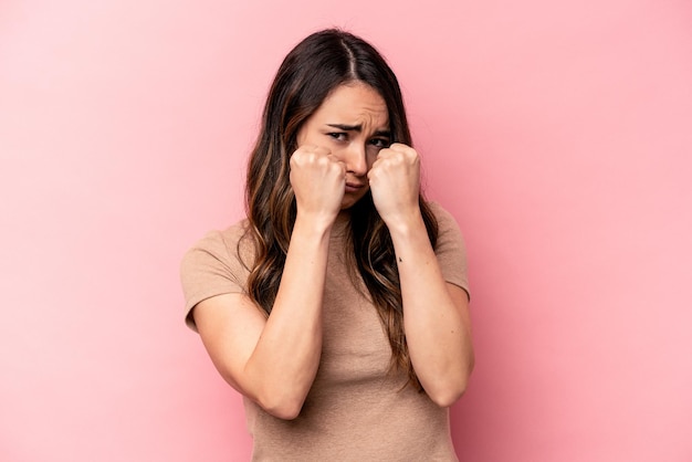 Young caucasian woman isolated on pink background throwing a punch anger fighting due to an argument boxing