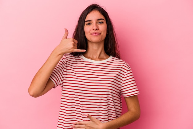 Young caucasian woman isolated on pink background touches tummy, smiles gently, eating and satisfaction concept.