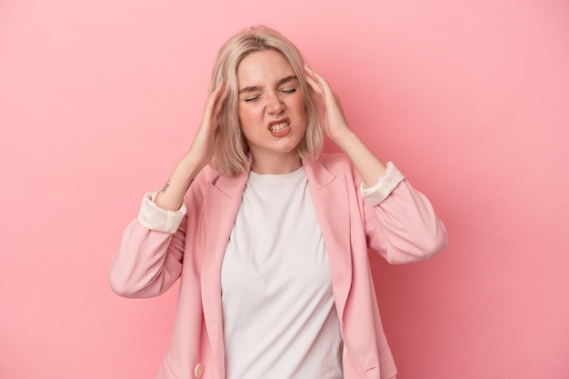 Young caucasian woman isolated on pink background touching temples and having headache.