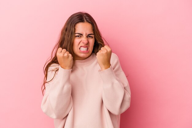 Young caucasian woman isolated on pink background  upset screaming with tense hands.