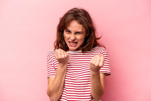 Young caucasian woman isolated on pink background upset screaming with tense hands