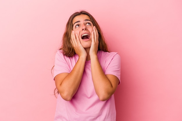 Young caucasian woman isolated on pink background  whining and crying disconsolately.