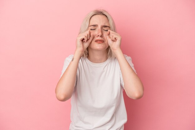 Photo young caucasian woman isolated on pink background whining and crying disconsolately.