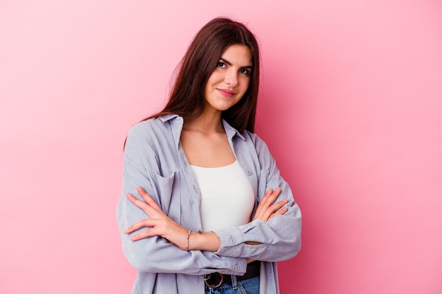 young caucasian woman isolated on pink background who feels confident, crossing arms with determination.