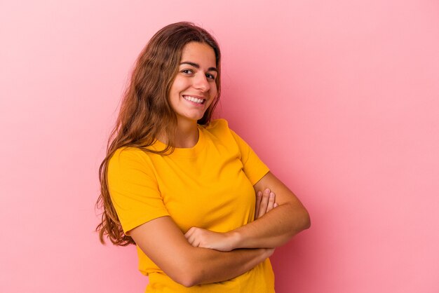 Young caucasian woman isolated on pink background  who feels confident, crossing arms with determination.