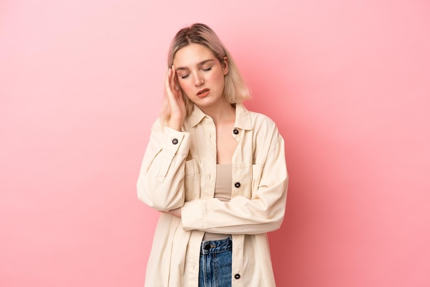 Young caucasian woman isolated on pink background with headache