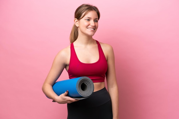 Young caucasian woman isolated on pink background with a mat