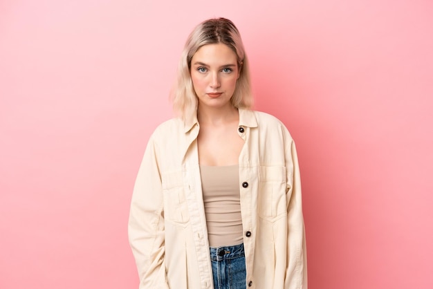 Young caucasian woman isolated on pink background with sad expression