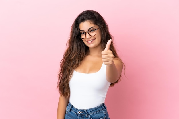 Young caucasian woman isolated on pink background with thumbs up because something good has happened