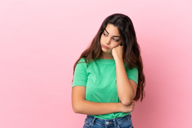 Young caucasian woman isolated on pink background with tired and bored expression