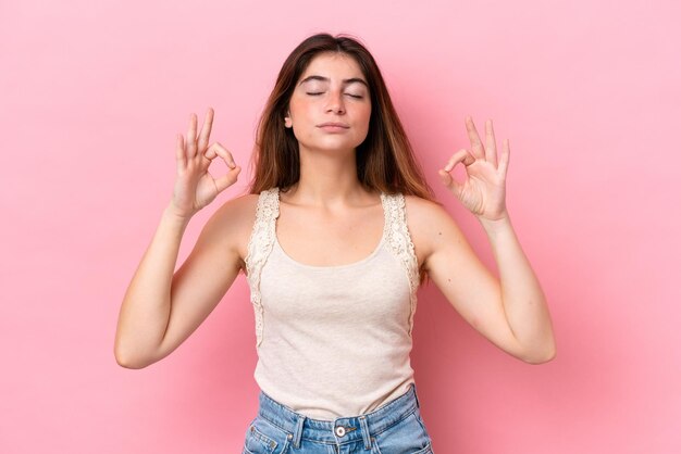 Young caucasian woman isolated on pink background in zen pose