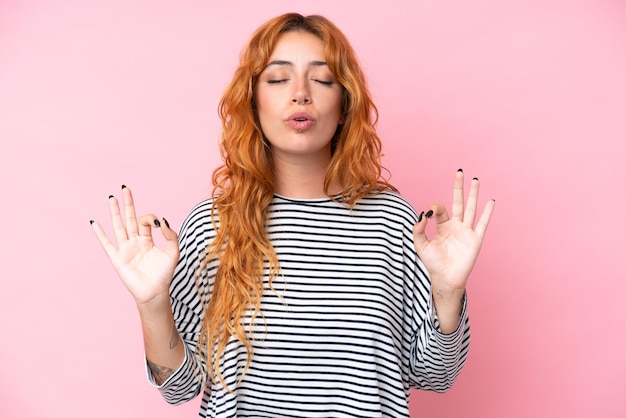 Foto giovane donna caucasica isolata su sfondo rosa in postura zen