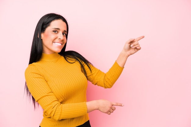 Young caucasian woman isolated on a pink excited pointing with forefingers away.