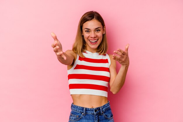 Young caucasian woman isolated on pink feels confident giving a hug