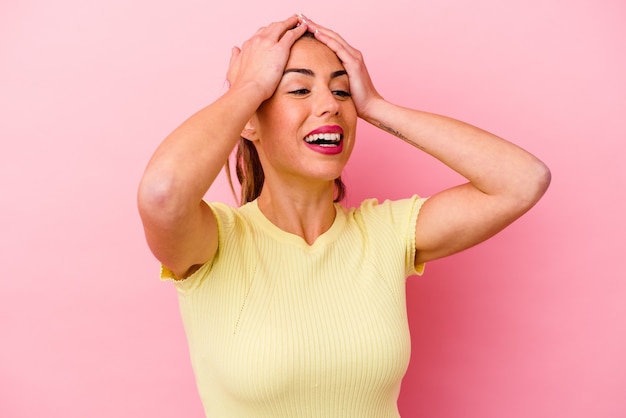 Young caucasian woman isolated on pink saying a gossip, pointing to side reporting something.