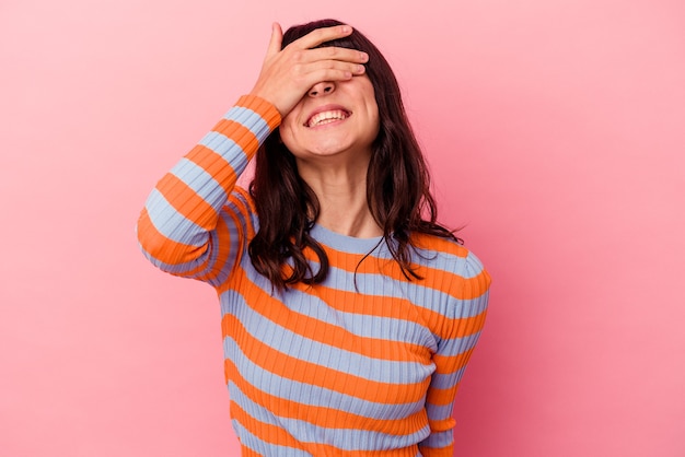 Young caucasian woman isolated on pink wall covers eyes with hands, smiles broadly waiting for a surprise.