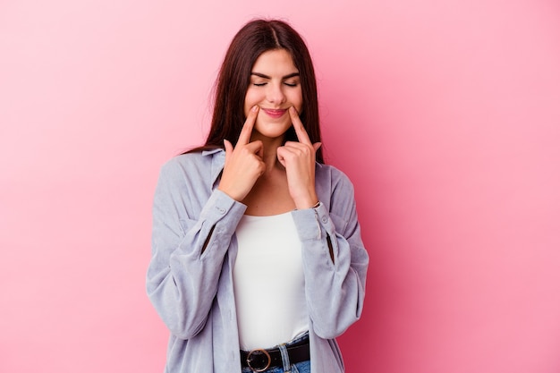 Young caucasian woman isolated on pink wall doubting between two options.