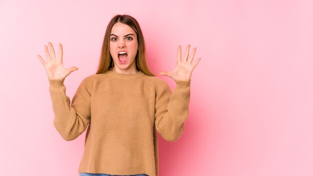 Young caucasian woman isolated on pink wall screaming to the sky, looking up, frustrated.