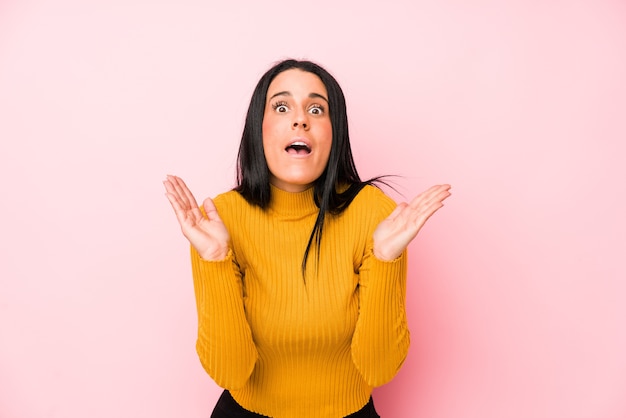 Young caucasian woman isolated on a pink wall surprised and shocked.