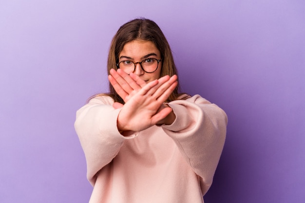 Foto giovane donna caucasica isolata su sfondo viola che fa un gesto di rifiuto