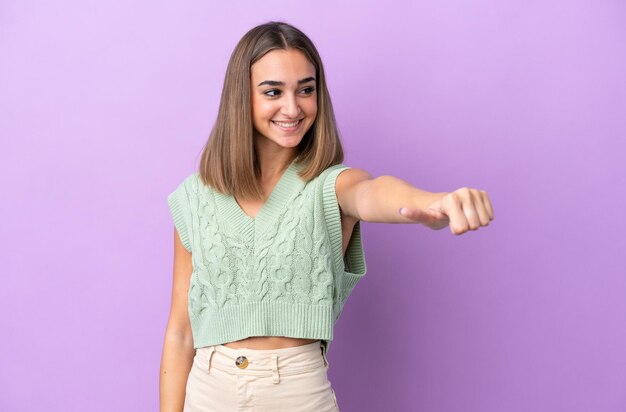 親指を立てるジェスチャーを与える紫色の背景に分離された若い白人女性