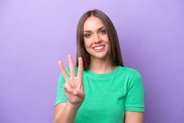 Young caucasian woman isolated on purple background happy and counting three with fingers