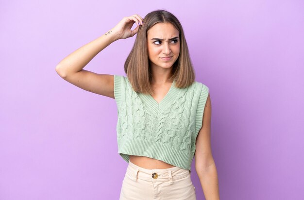 Young caucasian woman isolated on purple background having doubts while scratching head